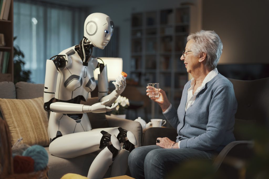 An elderly person sits with a medical robot