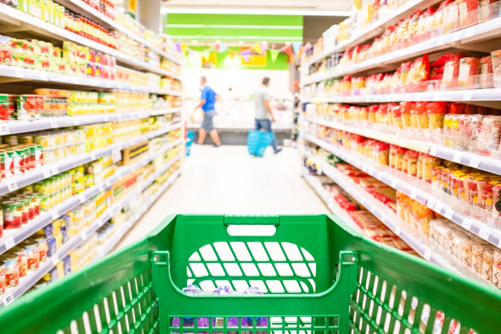 View of a shopping trolly in the middle of a supermarket aisle  