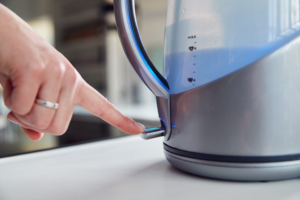 A woman switches on an electric kettle