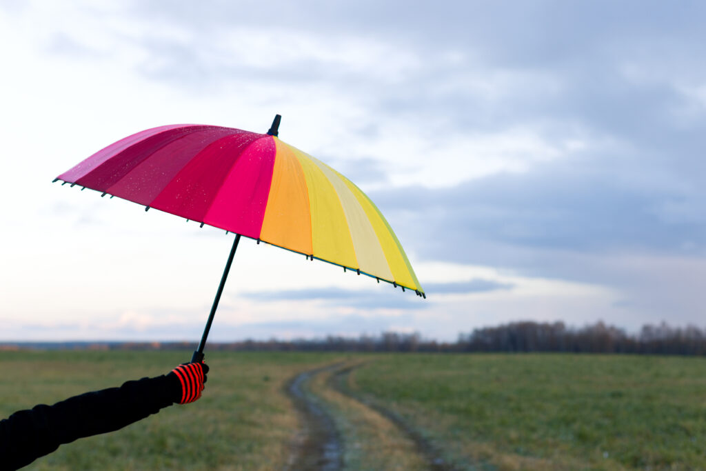 A bright umbrella being held aloft in the rain