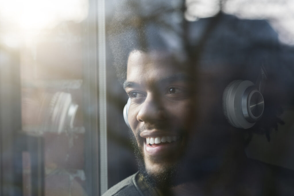 A man wearing headphones looks out the window