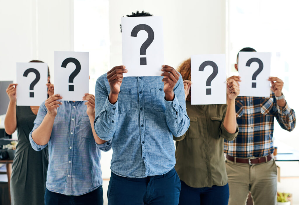 Shot of a group of people holding questions marks in front of their faces.