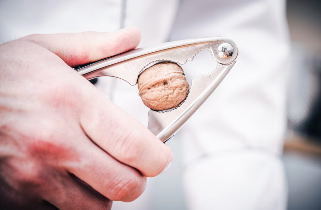 A man cracks a walnut with a nutcracker